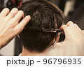 Young man getting a modern haircut. Girl hairdresser cuts a guy with scissors. Men's fashion and 96796935
