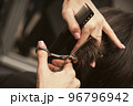 Hairstylist does cutting hair tips of a female customer in a beauty salon. Womens fashion and style 96796942