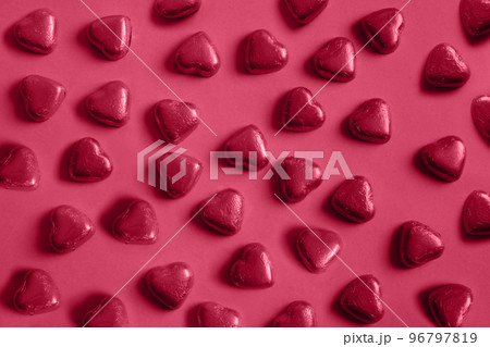Pattern of sweets as heart in foil. Trending color of 2023 - Viva Magenta. 96797819