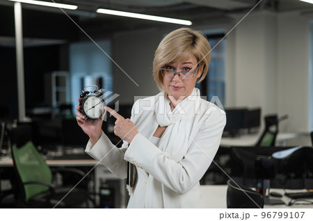 Caucasian business woman showing on alarm clock in office.  96799107
