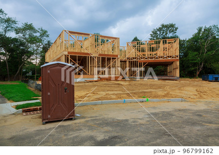 Portable restroom on a new structure near a new house under construction. Portable restroom on a new structure near a new house under construction. 96799162
