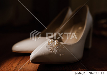 Earrings with pearls on white women's leather shoes. Bride's accessories, bride's morning 96799814
