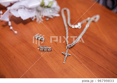 Earrings, a gold ring with a gem and a silver chain with a cross on a brown background Earrings, a gold ring with a gem and a silver chain with a cross on a brown background 96799833