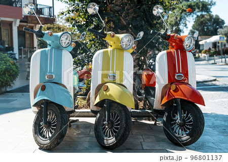 Scooter motorcycle on city street. Vintage classic retro scooters various bright colors on a sunny tourist street. Lifestyle, retro concept. Scooter motorcycle on city street. Vintage classic retro scooters various bright colors on a sunny tourist street. Lifestyle, retro concept. 96801137