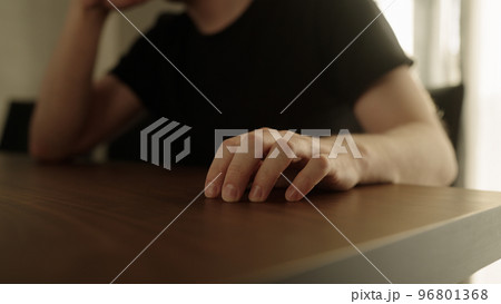 Man finger tap on walnut wood table indoor 96801368