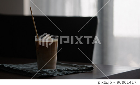 man making iced coffee with milk in thumbler glass on walnut table man making iced coffee with milk in thumbler glass on walnut table 96801417