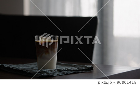 man making iced coffee with milk in thumbler glass on walnut table man making iced coffee with milk in thumbler glass on walnut table 96801418