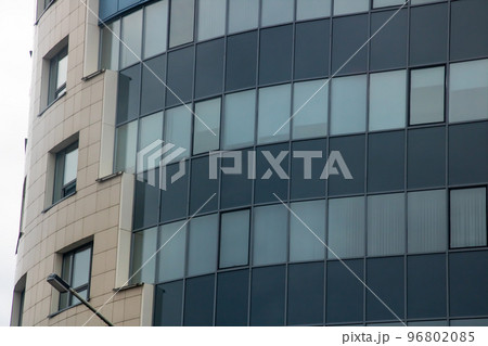 Tall glass modern building against a gray sky Tall glass modern building against a gray sky 96802085