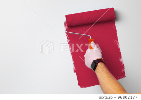 Gloved male hand painting wall into classic magenta color. Color of the year 2023, viva magenta. Gloved male hand painting wall into classic magenta color. Color of the year 2023, viva magenta. 96802177