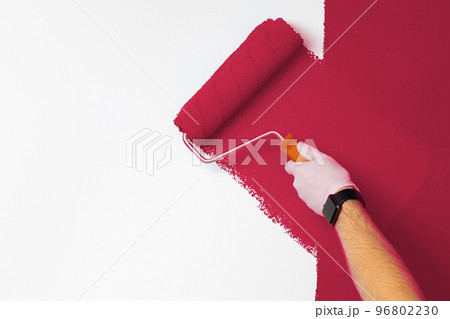 Gloved male hand painting wall into classic magenta color. Color of the year 2023, viva magenta. 96802230
