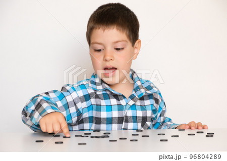 A 4-year-old boy is learning to count, teaching black numeracy chips for preschoolers A 4-year-old boy is learning to count, teaching black numeracy chips for preschoolers 96804289