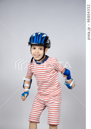 A happy 5-year-old boy in a protective helmet, elbow pads and gloves has fun A happy 5-year-old boy in a protective helmet, elbow pads and gloves has fun 96804352