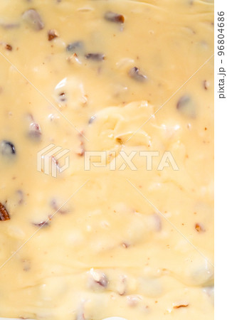 Pouring fudge mixture into the baking pan lined with parchment paper to prepare white chocolate cranberry pecan fudge. 96804686