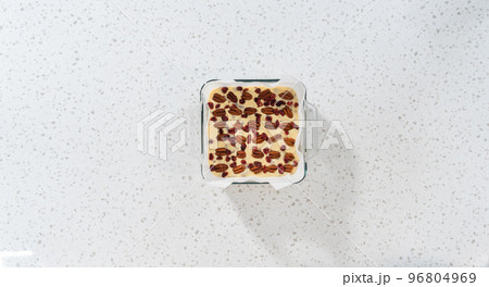 Flat lay. Removing white chocolate cranberry pecan fudge from the baking pan lined with parchment. 96804969