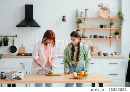 Two girlfriends cut fruit in the kitchen 96806061