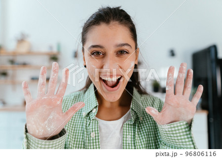 Young woman shows her hands in flour in the kitchen Young woman shows her hands in flour in the kitchen 96806116