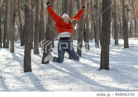Walk through the winter wood on sunny day. Happy young woman in snowy forest jumps high 96806240