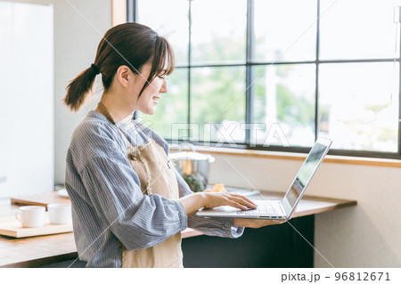 キッチンでノートパソコンを使ってレシピ検索・料理動画を見る家政婦・料理代行のアジア人女性 キッチンでノートパソコンを使ってレシピ検索・料理動画を見る家政婦・料理代行のアジア人女性 96812671