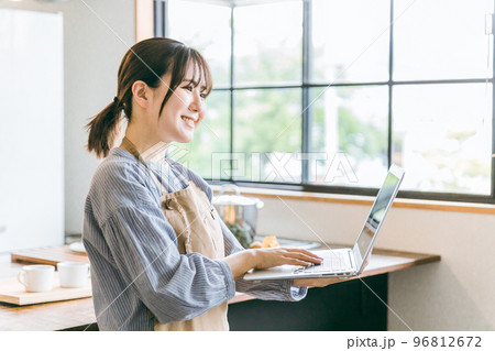 キッチンでノートパソコンを使ってを見るカフェスタッフのアジア人女性 キッチンでノートパソコンを使ってを見るカフェスタッフのアジア人女性 96812672