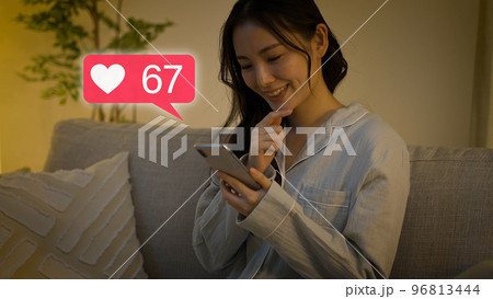 スマートフォンを操作をするパジャマ姿の若い女性 96813444