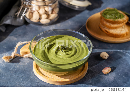 Pistachio cream in bowl with crostini on dark stone background 96818144