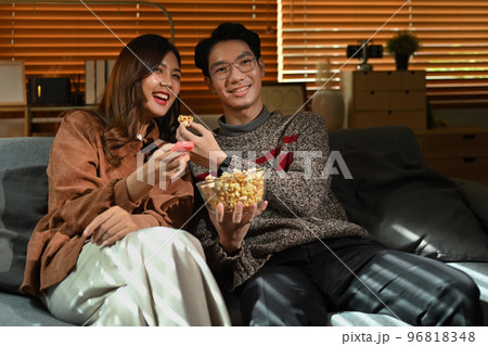Couple watching moving, television streaming services while sitting on a Couch in the living room 96818348