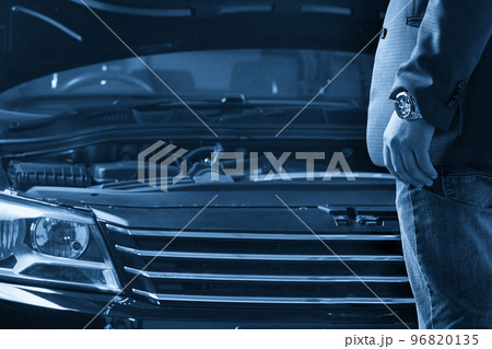 Man looking on the engine of a car with open hood 96820135