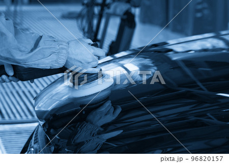 Man using polisher to polish black car body in the workshop 96820157