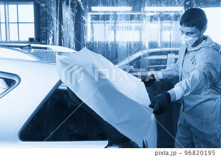 Mechanic covering car with paper before painting in auto repair service 96820195