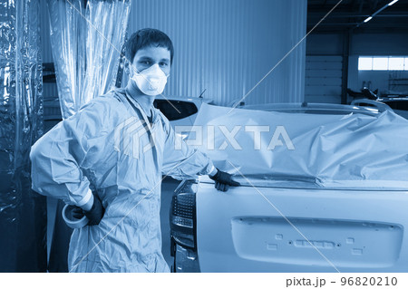 Mechanic covering car before painting in auto repair service 96820210