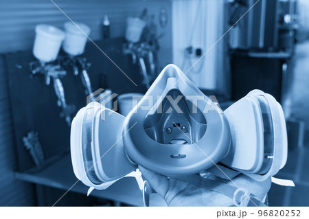Professional respirator in auto repair shop with spray guns on background 96820252