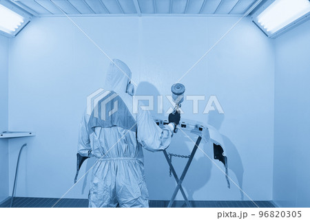 Mechanic painting bumper of a car with sprayer in painting booth in repair auto service 96820305