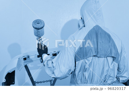 Mechanic painting bumper of a car with sprayer in painting booth in repair auto service 96820317