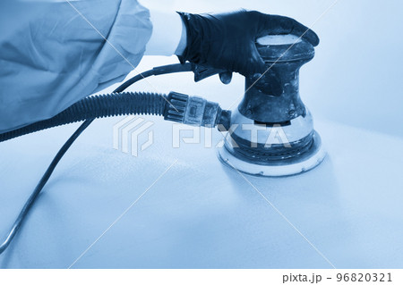 Auto mechanic buffing and polishing car in auto repair shop with orbital polisher, basic layer cleaning 96820321