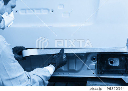 Mechanic covering car with duck tape before painting in auto repair service 96820344