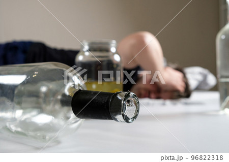 A drunk man lies in bed, holding his hands to his head. Hangover, alcoholic delirium. A drunk man lies in bed, holding his hands to his head. Hangover, alcoholic delirium. 96822318