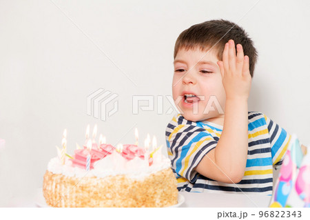 The boy is upset, celebrating his birthday, crying sitting at the table with a cake, a place for text. The boy is upset, celebrating his birthday, crying sitting at the table with a cake, a place for text. 96822343