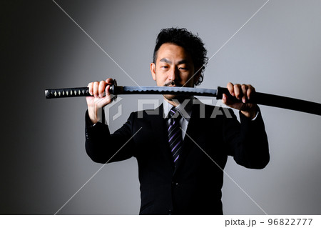 スーツのサラリーマンが刀を持っているところ 96822777