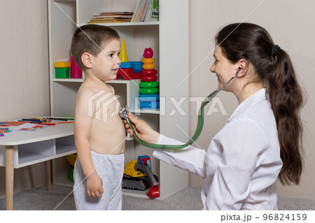 The pediatrician will auscultize the lungs and heart of a little boy 3-4 years old. Pediatrics, home-based doctor's appointment. 96824159