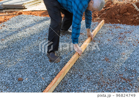 Two by fours wood lumber needed to be leveled on gravel for foundation deck in backyard shed Two by fours wood lumber needed to be leveled on gravel for foundation deck in backyard shed 96824749