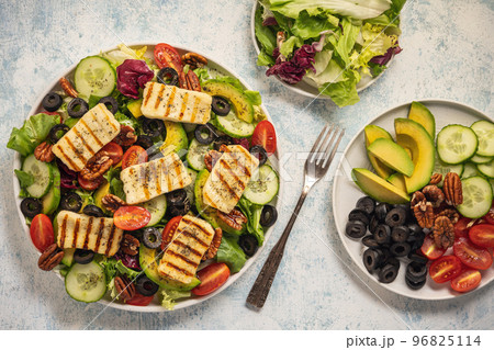 Greek style cuisine - salad with grilled halloumi cheese, avocado, pecan nuts and tomatoes. Greek style cuisine - salad with grilled halloumi cheese, avocado, pecan nuts and tomatoes. 96825114