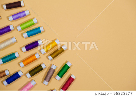 A set of multi-colored threads for sewing with an empty space for text on a beige background, top view. Tailoring and needlework equipment, tailor banner. 96825277