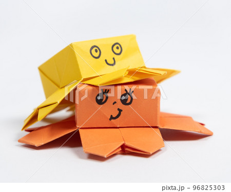 Two cute yellow and orange origami octopuses on a white background, paper animal figurines 96825303