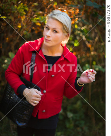 Pretty woman in a park on a sunny day wearing a red coat Pretty woman in a park on a sunny day wearing a red coat 96827270