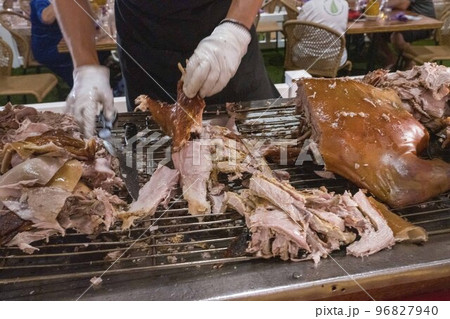 Chef cuts up baked pig pork to serve to guests at buffet Chef cuts up baked pig pork to serve to guests at buffet 96827940