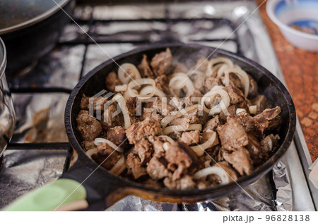 Fried veal liver with onions in a pan. Braised cow and pork liver 96828138