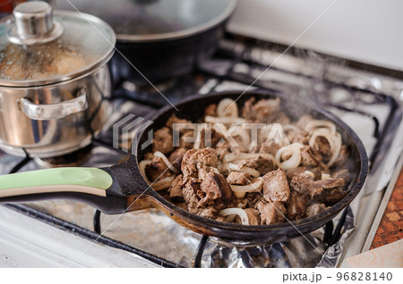 Fried veal liver with onions in a pan. Braised cow and pork liver 96828140