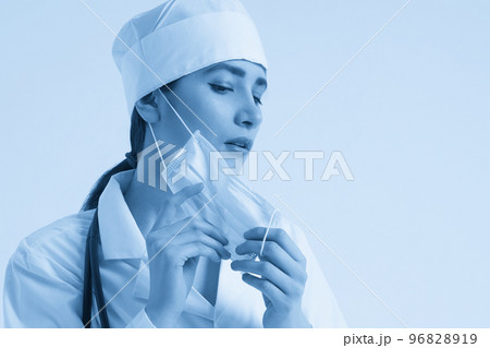 Portrait of young female doctor putting on protective medical face mask on white background, copy space Portrait of young female doctor putting on protective medical face mask on white background, copy space 96828919