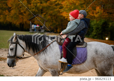 Two children are sitting on a horse, happy children are walking in the forest with a horse. 96829113