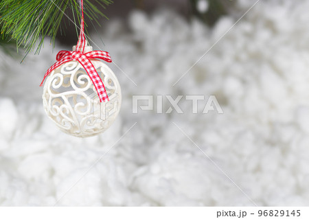 A white Christmas ball and a snow-covered tree branch on a snowy white background. Horizontal card place for copy space text A white Christmas ball and a snow-covered tree branch on a snowy white background. Horizontal card place for copy space text 96829145